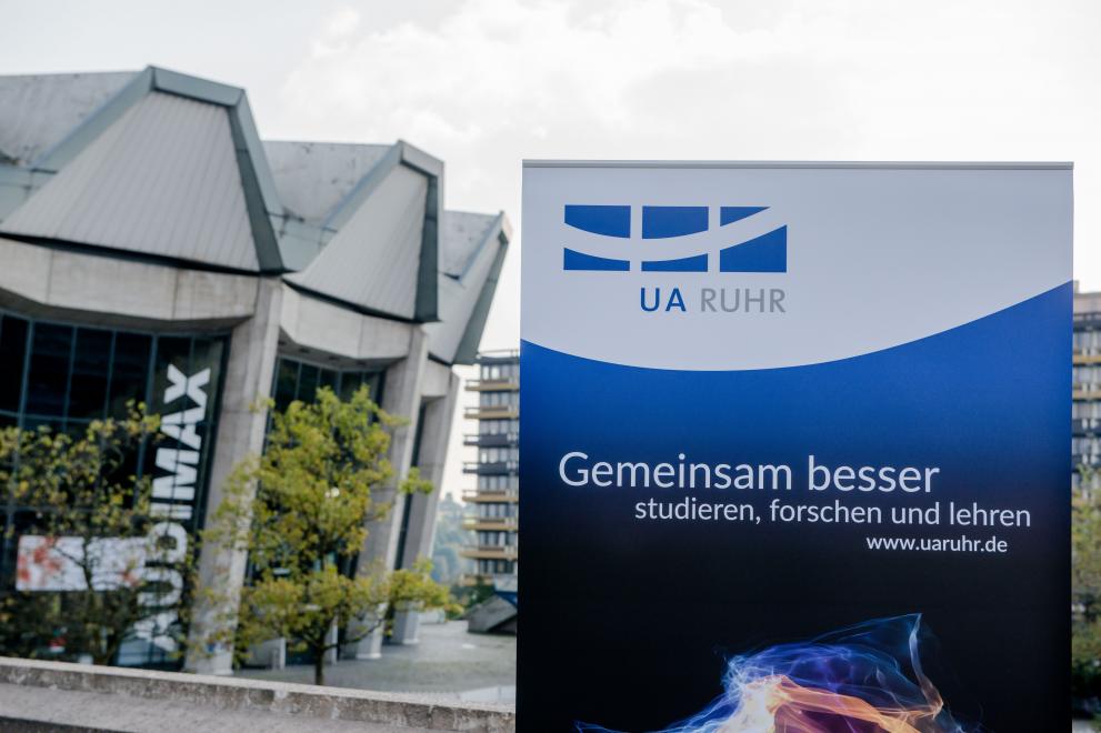 Poster of the University Aalliance Ruhr in front of the Audimax