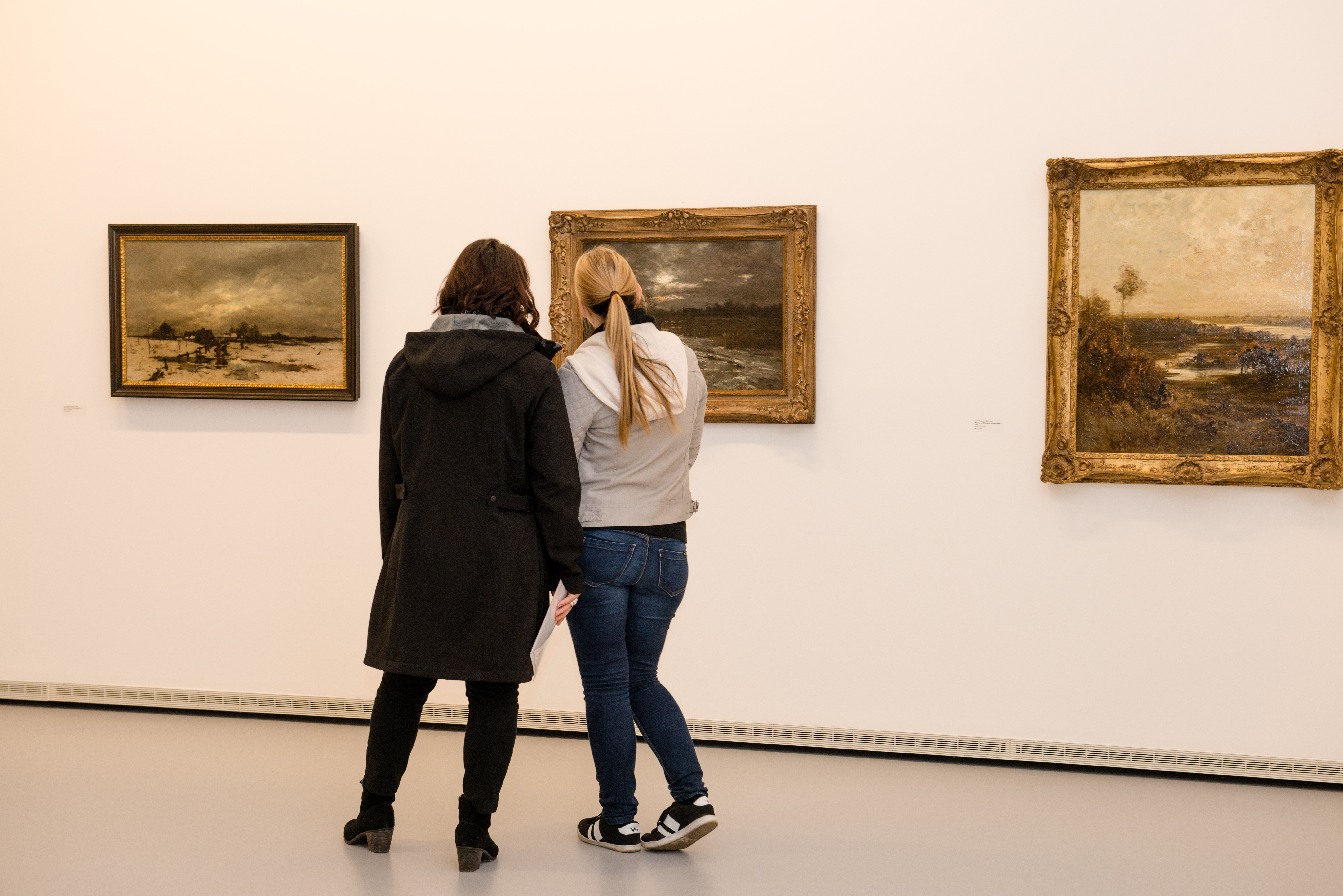 Zwei Frauen betrachten ein Bild in einem Museum.