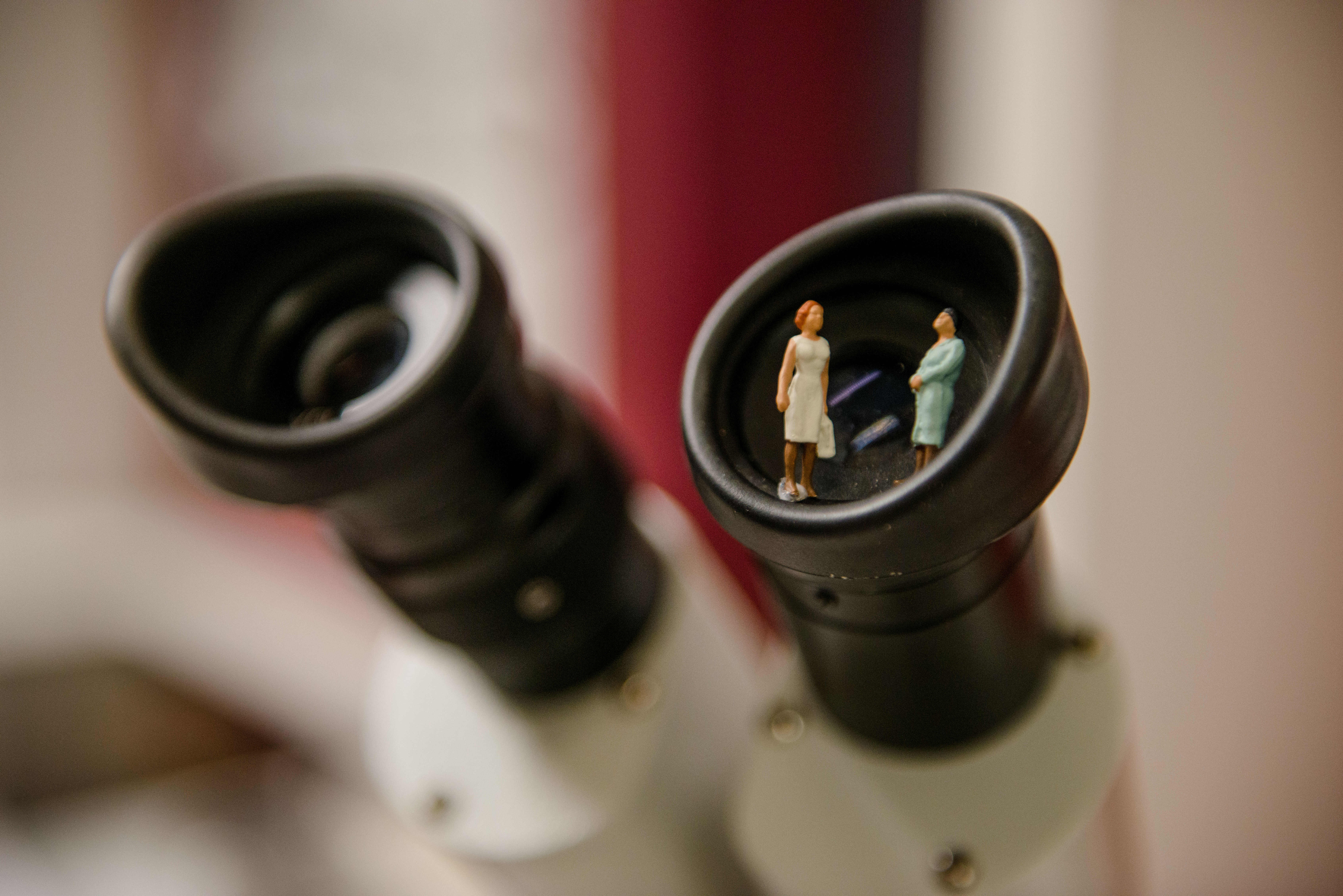 Puppen sitzen im Okular eines Mikroskops