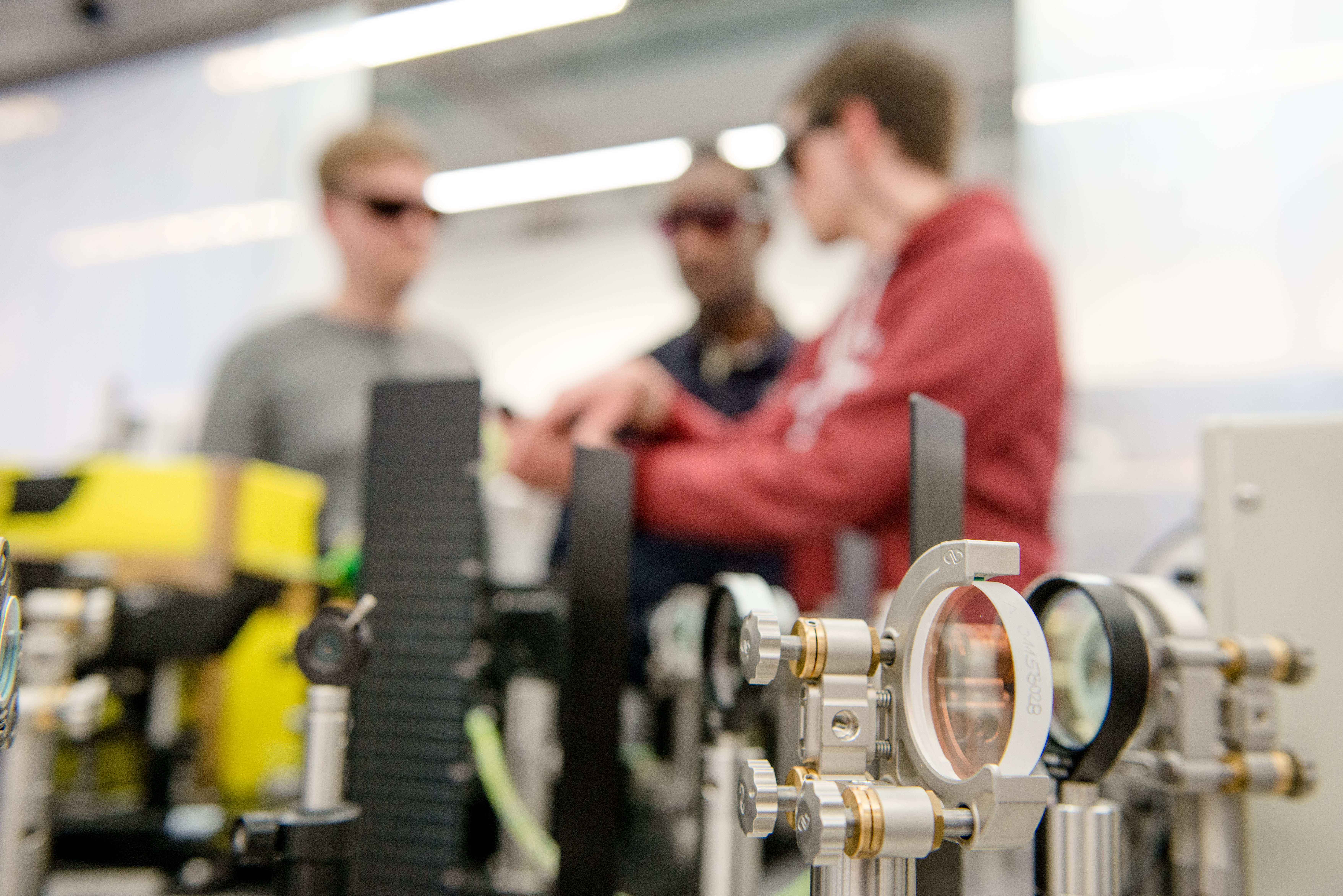 Drei junge Forscher in einem Laserlabor