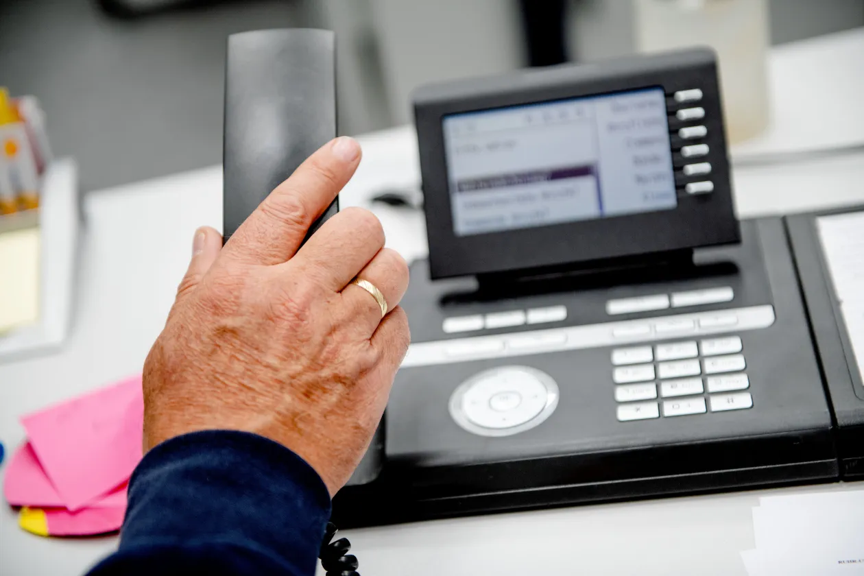 Eine Hand hebt einen Telefonhörer ab