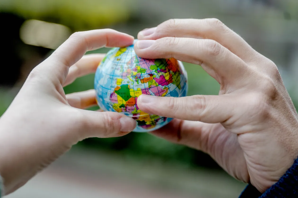 Hände halten eine kleine Weltkugel