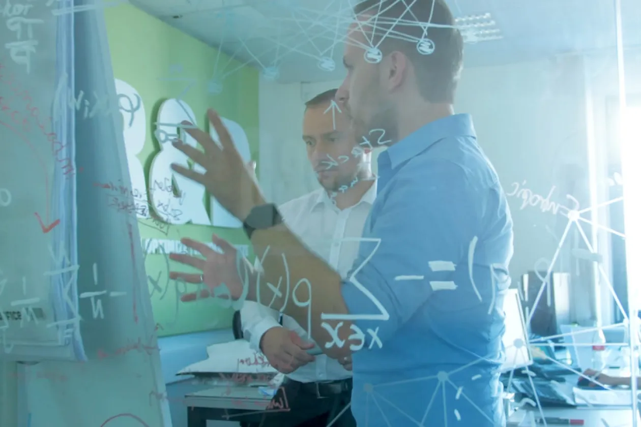 Zwei Männer unterhalten sich hinter einer beschriebenen Glaswand