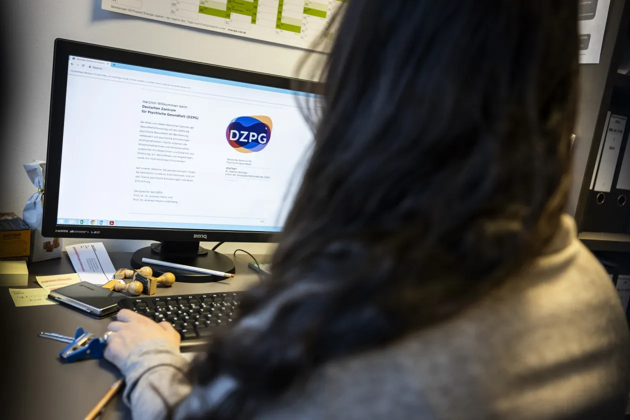 Frau sitzt vor einem Monitor, der die Webseite des DZPG zeigt