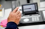 Eine Hand hebt einen Telefonhörer ab