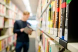 Mann in Bibliothek mit Büchern zur Informationstechnik