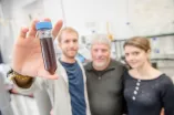 Researchers with a test tube with a dark liquid