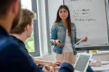 Foto: Eine junge Frau präsentiert etwas an einem Flipchart.