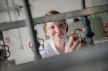 Studentin mit Schutzbrille dreht an einem Ventil