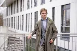 Ein Mann im Mantel lehnt an einem Geländer