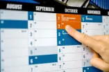 Wandkalender in den Farben des Ruhr Innovation Lab mit Hand, die auf 2. Oktober zeigt