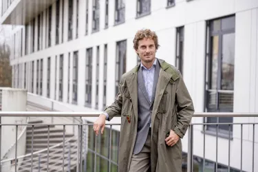 Ein Mann im Mantel lehnt an einem Geländer