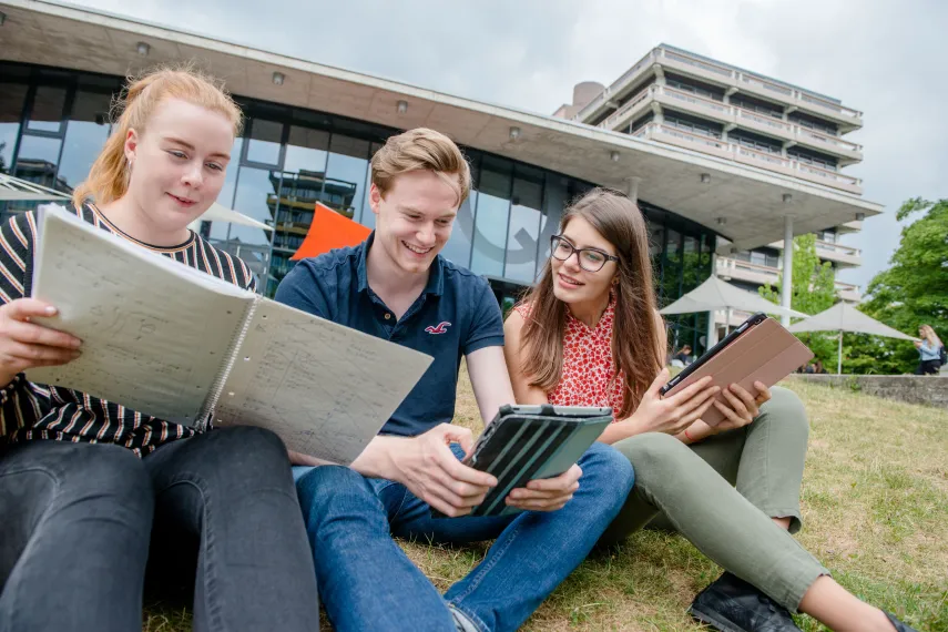 Drei junge Frauen mit Lernmaterial auf einer Wiese