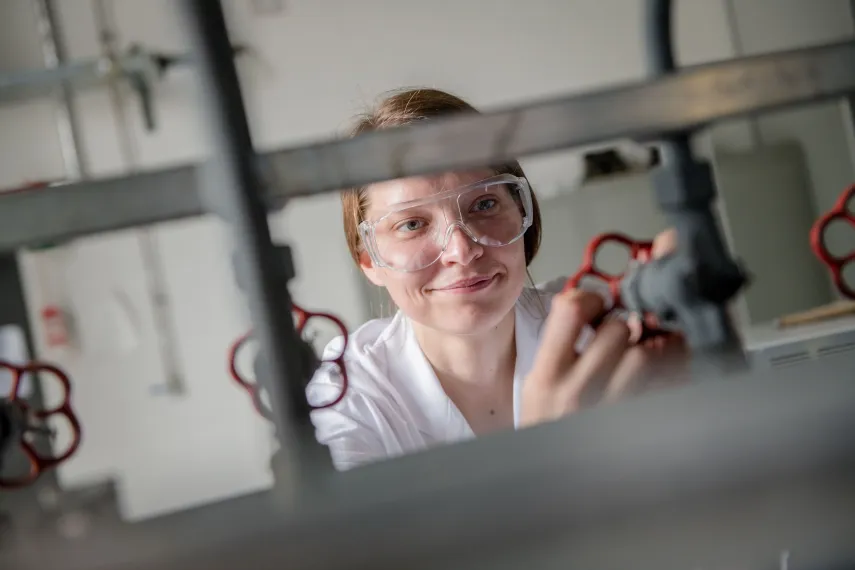 Studentin mit Schutzbrille dreht an einem Ventil