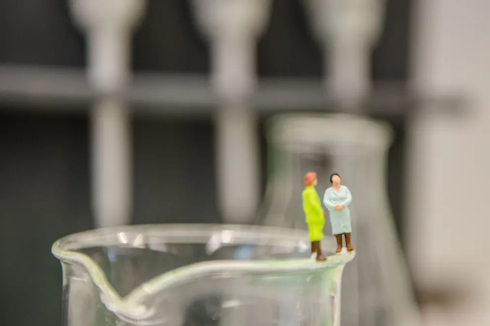 Modellfiguren auf dem Rand eines Becherglases