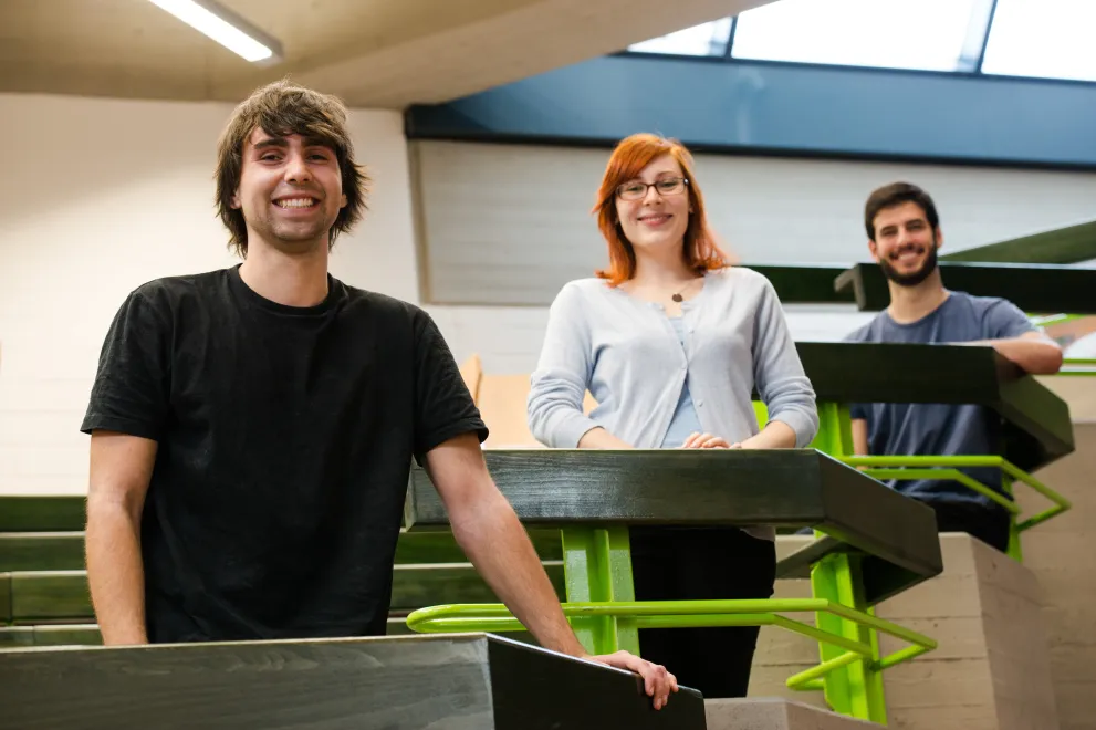 Drei junge Leute in einem Hörsaal