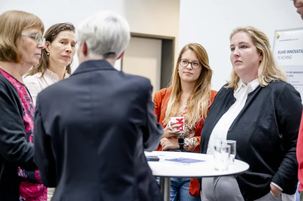 Mehrere Personen im Gespräch an einem Stehtisch