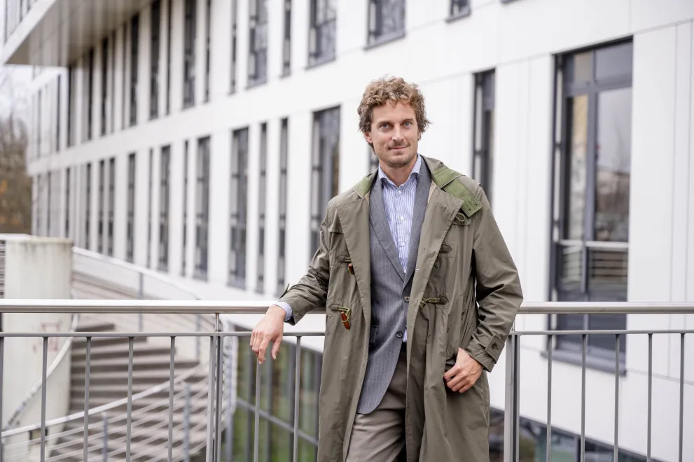 Ein Mann im Mantel lehnt an einem Geländer