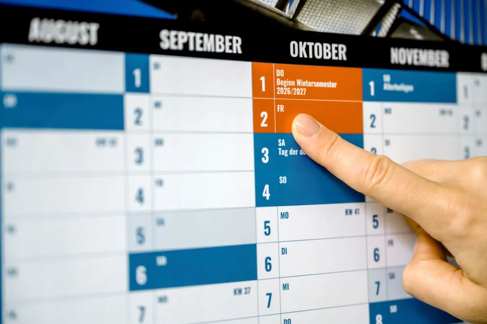Wandkalender in den Farben des Ruhr Innovation Lab mit Hand, die auf 2. Oktober zeigt